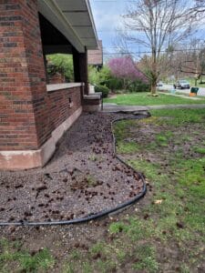 Old landscaping with rubber border next to a house